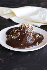 Chocolate profiteroles dessert on a dark wooden background