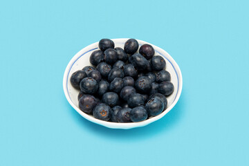 Blueberries in a plate on a blue background