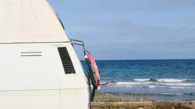 Camper van with surf board camping on beach sea shore.
