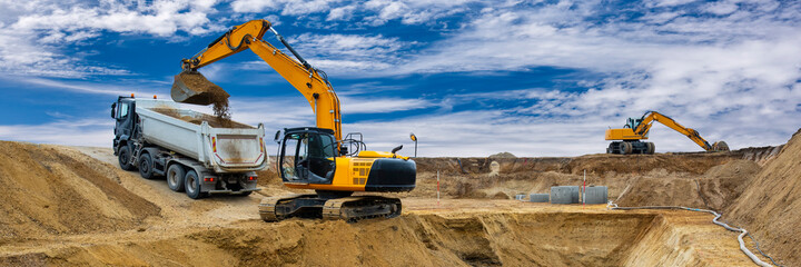 Bagger arbeitet auf einer Baustelle mit dramatischen Wolken