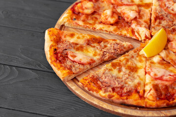 Close up of freshly baked pizza on black wooden table