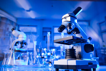 Laboratory investigations concerning covid pandemy. Microscope, glass tubes and beakers in the laboratory.