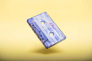 falling vintage audio cassette on yellow background.