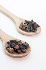 Dry brown spice cloves on wooden spoon - cooking ingredients