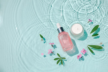 Moisturizing cosmetic products on water with drops. Serum glass bottle and cream jar on aqua...