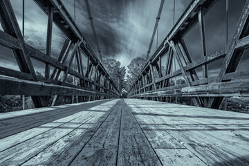 An old wooden bridge over the river for bicycles and pedestrian traffic in Sweden. (Dalälven Älvkarleby).