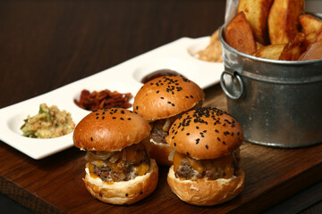 Craft beef burger and french fries on wooden table isolated on black background.