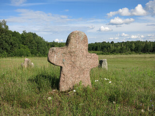 An old pagan cemetery in Belarus. Stone gray granite cross, humanoid