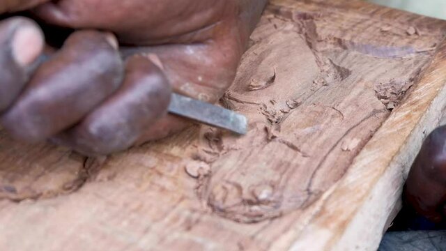 Wood carver using a small chisel and carving a fish into wood
