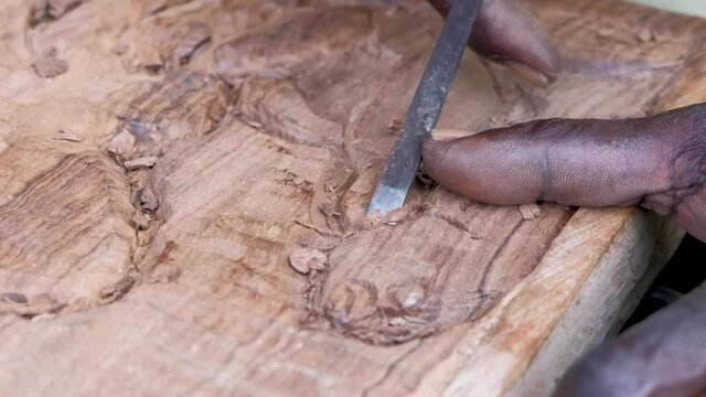 Talented wood carver carving a fish with a small chisel in Bougainville, Papua New Guinea
