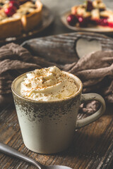 Cup of coffee with cream and cinnamon powder on an antique book on a wooden tray with fresh cherries, coffee break, vertical