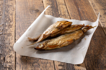 Three smoked vendace fish on wooden background.