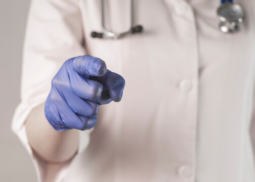 Doctor closeup pounting at you with index finger, gesturing with hand in glove.