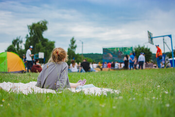 Summer cinema. Girl sitting on the lawn watching a movie in the open air.