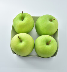 four green apples in a cardboard box