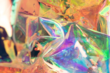 Defocused iridescent holographic background. Blurred colorful texture of wrinkled foil.