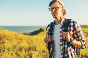 Naklejka na ściany i meble young man, in glasses and in a cap with a backpack, hiking and enjoying the mountain landscape, adventure man hiking in the desert mountains