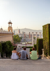 A group of 3 tourist enjoying the sunset at the top of a steps in Barcelona.