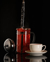 Brewing tea. Water flow falls into glass teapot on black background. Tea ceremony concept. Cup of...