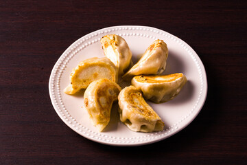 oriental dish. grilled ravioli over dark wooden table. detail