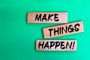 Make things happen! words made on wooden building blocks green background.