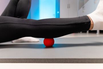 Close-up of self-massage of a sports woman indoors using a massage ball. Myofascial massage without...
