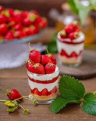 Strawberry dessert in a glass with a decor of cut strawberries standing on a wooden background