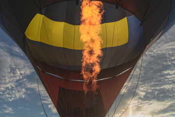 Hot flame from a gas burner light up inside of a hot air balloon at evening.