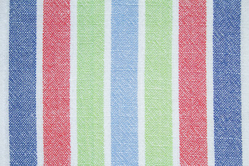 Linen white fabric with an ornament. Pattern in the form of vertical stripes. Stripes in red, green, blue and light blue. The stripes are located symmetrically from the center. A texture or background