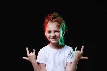 child girl with crazy expression doing rock symbol with hands up
