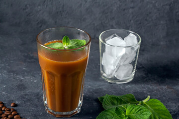 Recipe Ice coffee with mint and milk. Big glass of coffee cocktail and glass with ice cubes. Cool summer drink on dark background in law key. copy space for text.