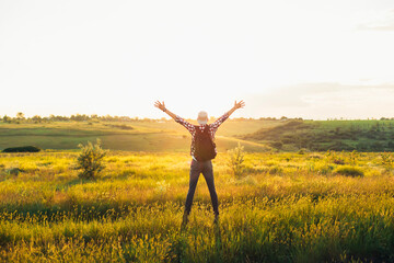 Rear view of man jumping up with outstretched arms, happy man with arms up against blue sky background, outdoors