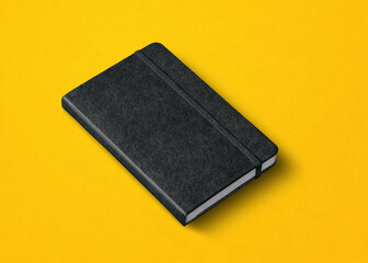 black closed notebook isolated on yellow