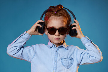 redhead child girl in sunglasses and wireless headphones