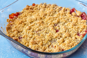 Home сooking. Rhubarb or Strawberry crumble, gluten free crisp in baking dish. Summer dessert on blue background.