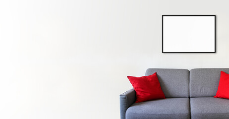 Empty picture frame on a white wall above a sofa. Horizontal banner