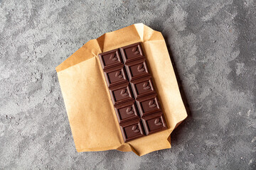 Bar of brown chocolate dark background. Candy sweet dessert and snack. Dark chocolate is antioxidant and boosts energy and serotonin. Close up.