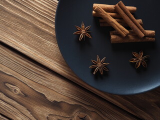 Star anise and cinnamon on a blue plate on a wooden background