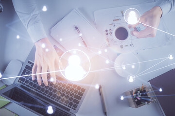 Double exposure of man's hands typing over computer keyboard and social network theme hologram drawing. Top view. People connection web concept.