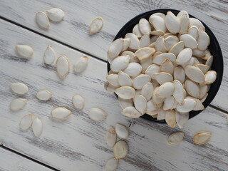 Pumpkin seeds in a black cup on a light wooden background
