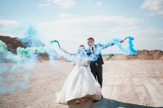 Newlyweds in a career. The guy and the girl hug and hold colored smoke in their hands