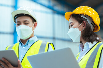 Chief industrial engineer inspects the mask factory. Discuss new projects while using a laptop. They showed an assertive attitude. There are employees wearing protective gear working diligently.