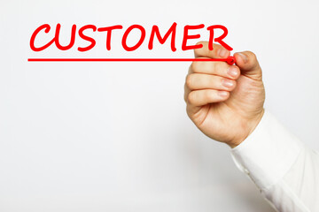A businessman in a white shirt writes a text CUSTOMER on a white background with a red marker . business concept