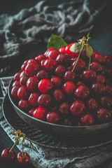 Ripe cherries in a black bowl on black background, vertical