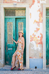 Portrait of an attractive tourist woman in old town Wearing stylish long dress, bracelets and straw hat.