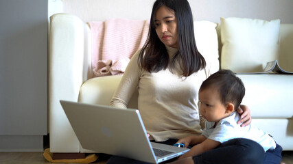Asian mother working from home while her son playing