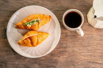 hot coffee in white ceramic mug on old wooden table,croissant in white plate and coffee kettle
