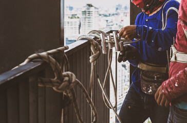 Industrial worker adjusting climbing gear preparing safety rope.