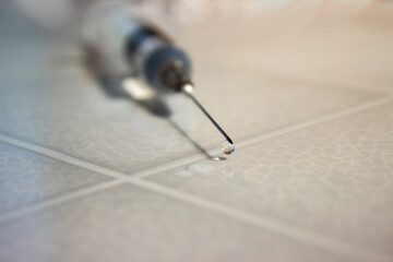 Close-up of droplet on the tip of a syringe needle. Healthcare, pharmaceutical industry, drug abuse and vaccination concepts