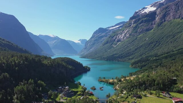 Spectacular view of Loen turquoise glacier water among epic mountain scenery with deep valley and snow capped mountains - Reverse aerial Loen Nordfjord Norway